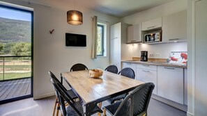 A modern kitchen with a dining area, a TV, and a view of the outdoors. - Savoie Family Retreat for 6 (Motz)
