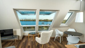 Et moderne loftværelse med ovenlys, spiseplads og udsigt til en sø.