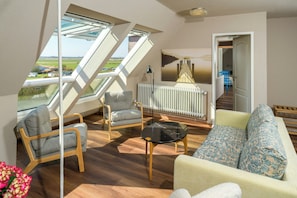 Una sala de estar moderna con un sofá, sillones, una mesa de centro de vidrio y vistas a través de tragaluces.