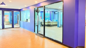 Un espace d’accueil d’hôtel comprenant un comptoir de réception, des portes vitrées et un mur bleu.