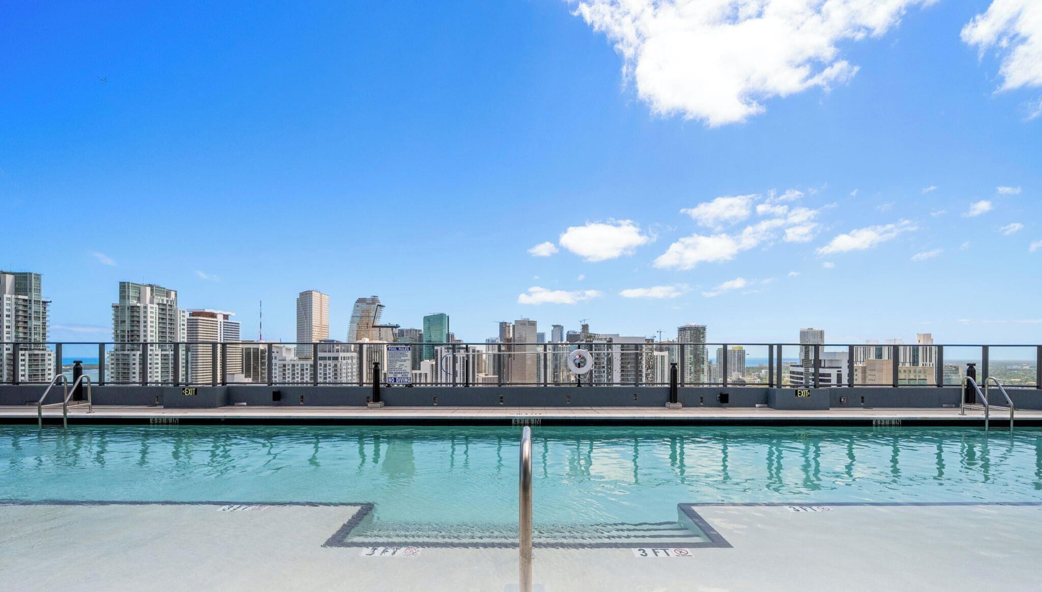 Pool på taget med udsigt til byens skyline, metalgelændere og 'EXIT'-skilte.