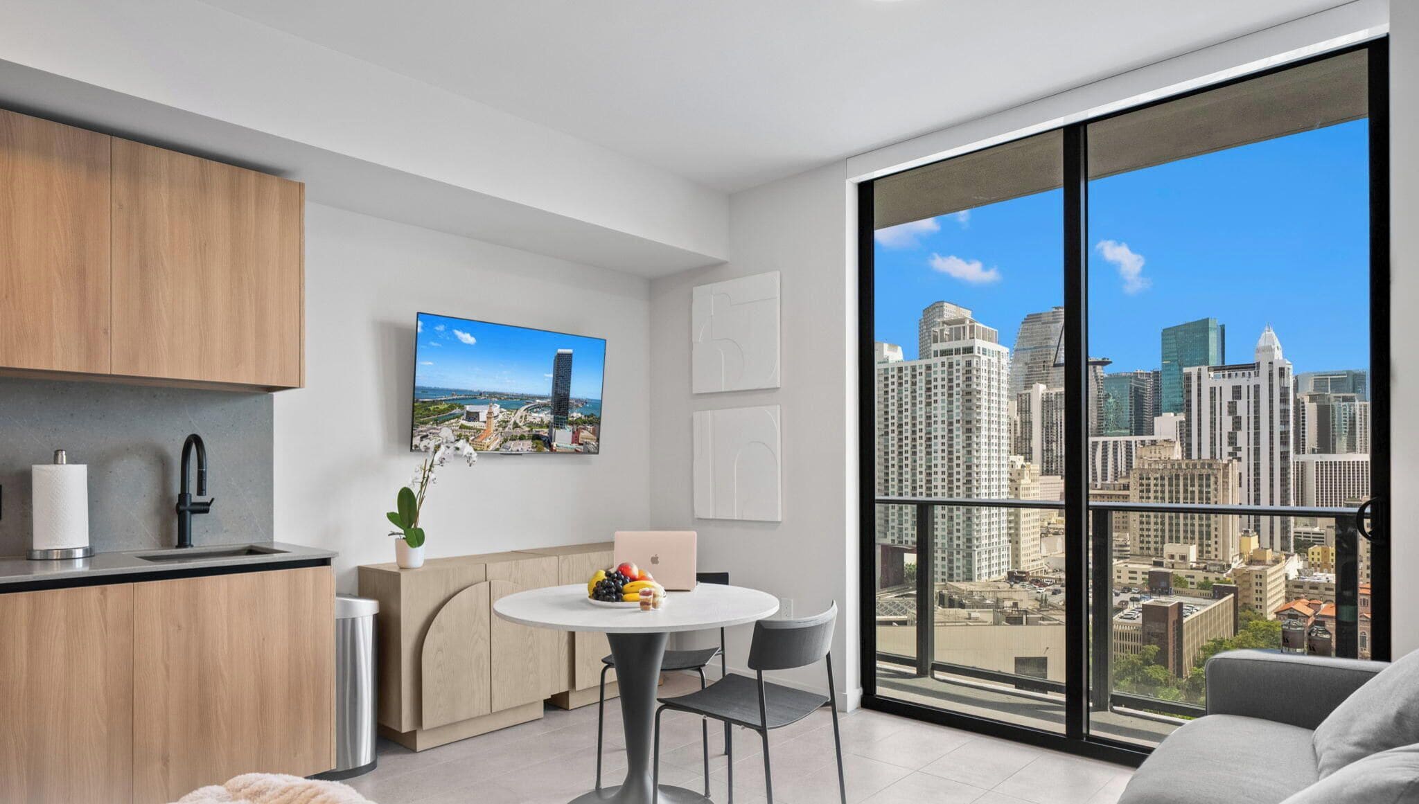 A modern apartment with a kitchen, dining area, and a large balcony with a city view.