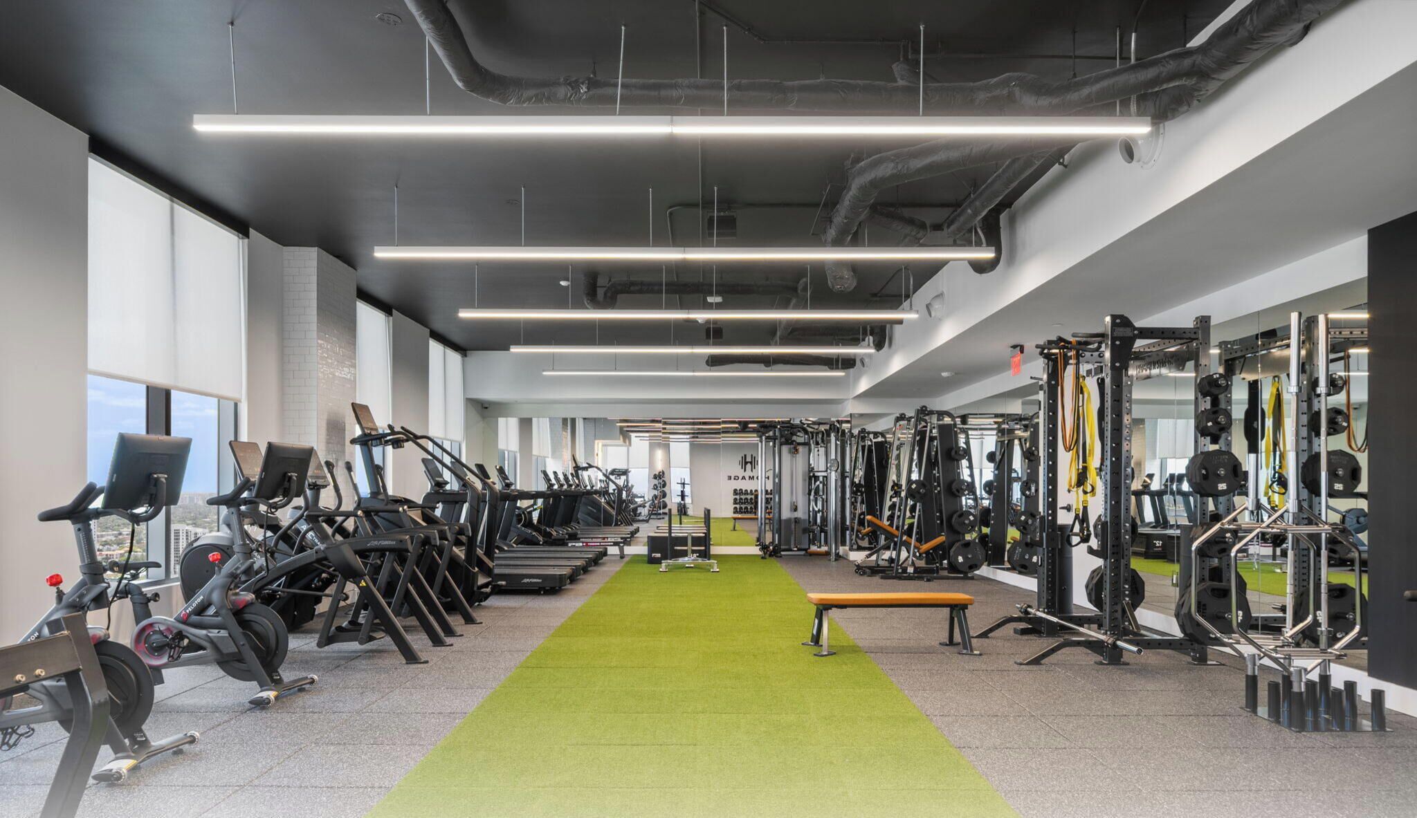 Une salle de sport équipée de tapis de course, d’appareils de musculation et dotée d’un revêtement de sol vert.