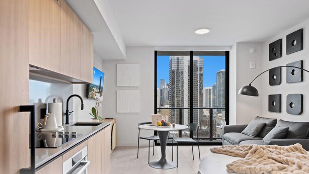 A modern apartment with a kitchen, dining area, and living room, featuring a large window with a city view. - Downtown Miami near Science&Art Museums (Miami)