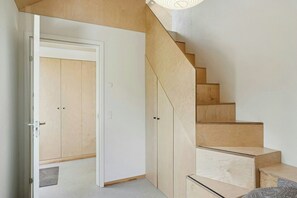 A wooden staircase leading to a room with a white door and a closet.