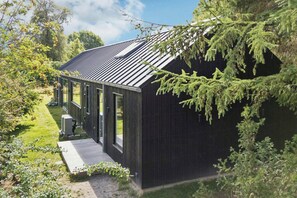 A modern house with a sloped roof, large windows, and a covered porch.