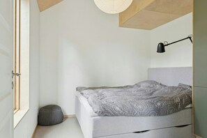 A minimalist bedroom with a bed, bedside lamp, and a window.