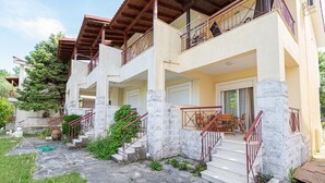 A multi-story building with stone steps, balconies, and a garden area. - Chrysanthos Maisonette by RentalsPro - Siviri Halkidiki (Siviri)