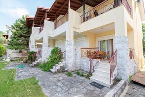 A multi-story building with stone steps, balconies, and a garden area. - Chrysanthos Maisonette by RentalsPro - Siviri Halkidiki (Siviri)
