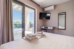 Une chambre d’hôtel avec un lit, une télévision, un miroir et un balcon offrant une vue.