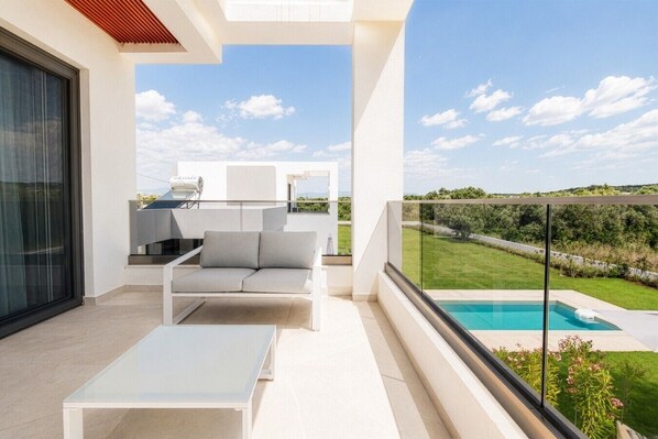 Un balcon avec une piscine, un canapé et une table.
