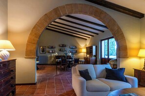 Un soggiorno con un arco in pietra, un divano, un tavolino da caffè e un'area pranzo con sedie e tavolo.