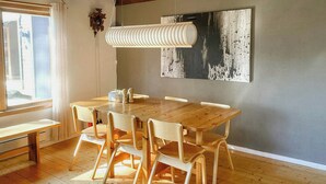 Un comedor con una mesa y sillas de madera, una lámpara colgante y una pared decorada con un relieve artístico.