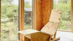 Una habitación con ventanas amplias, paredes de madera y una silla de madera.