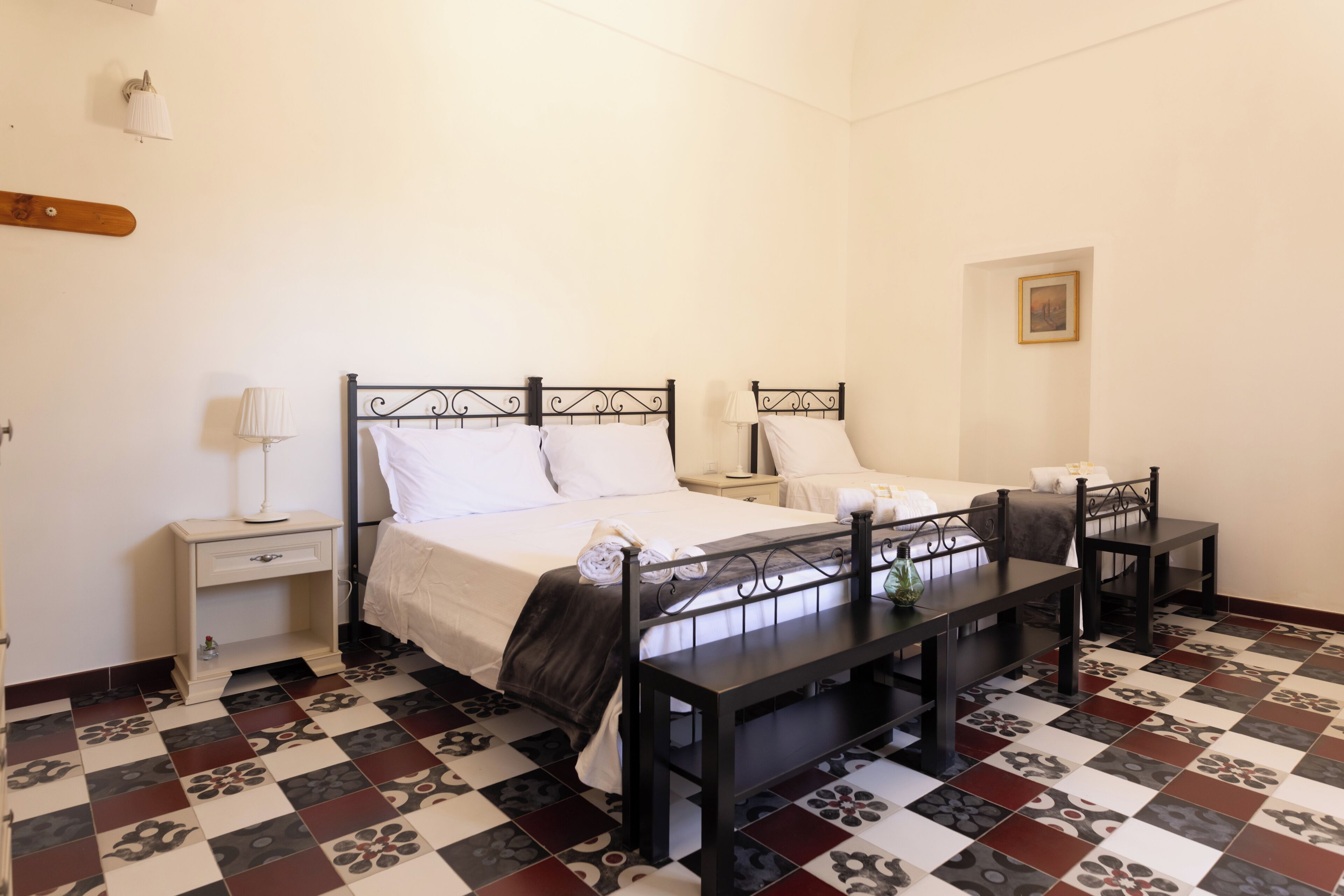 Una habitación de hotel con una cama, mesitas de noche, un escritorio y un suelo estampado.