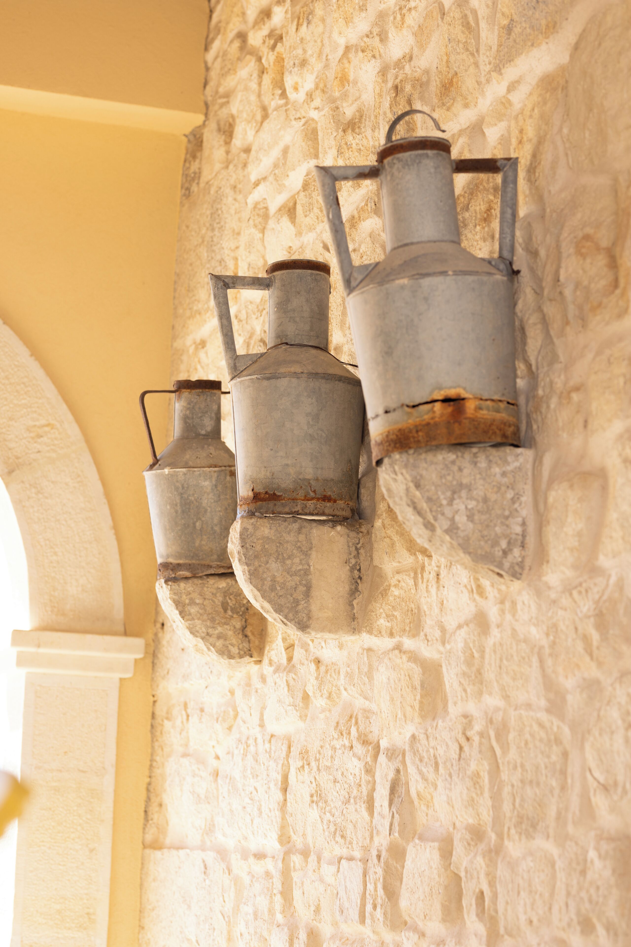 A stone wall with three metal lanterns attached to it.
