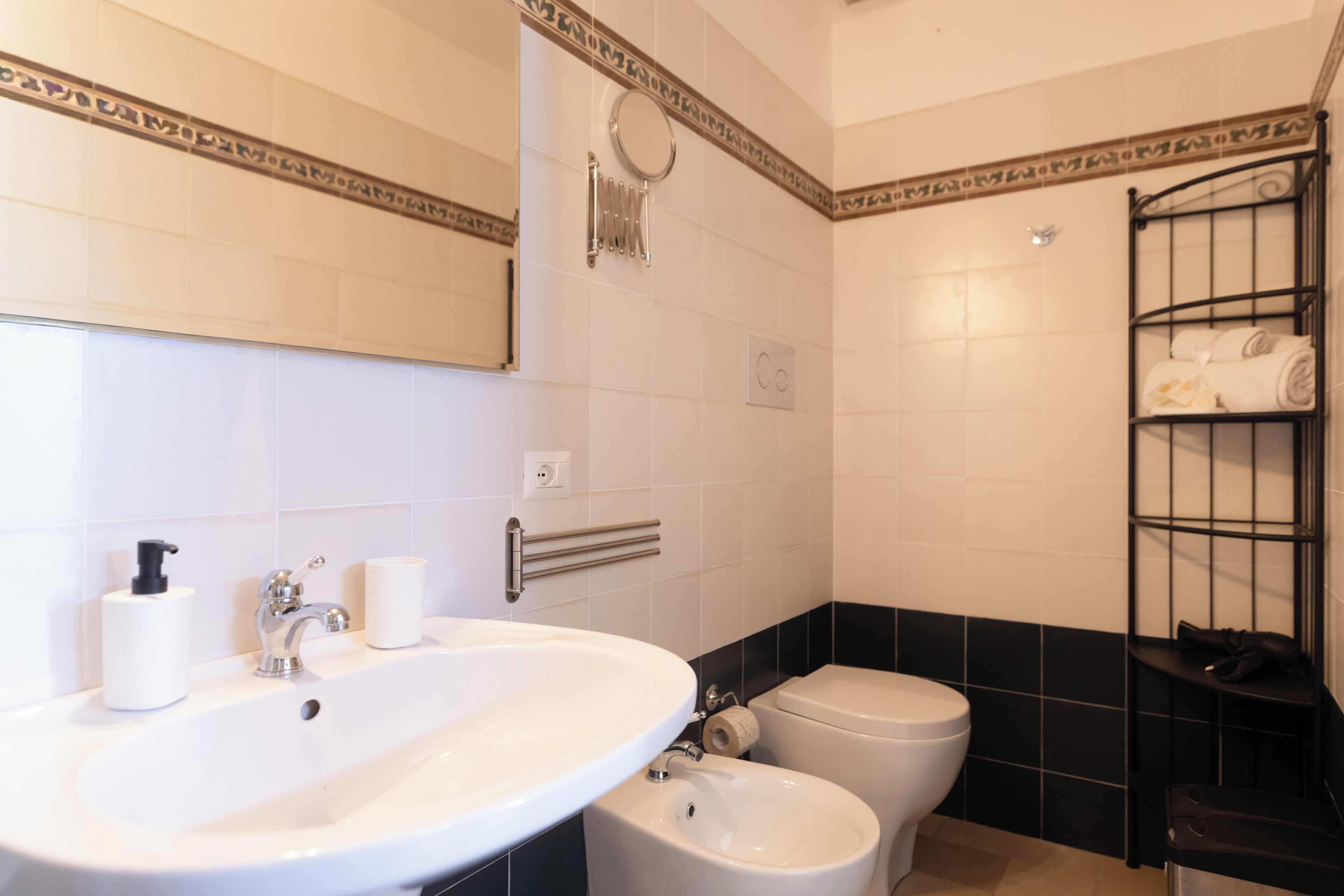 Un bagno con lavandino, due bacinelle, WC, portasci e specchio.
