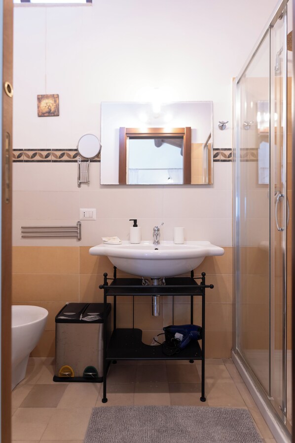 A bathroom with a sink, mirror, towel rack, and a glass shower enclosure.