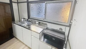 A kitchen with a double sink, a built-in oven, and a window with condensation. - Q stay Toneri Park (Tokyo)