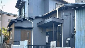 A two-story residential building with a dark exterior, a front porch, and a visible mailbox. - Q stay Toneri Park (Tokyo)