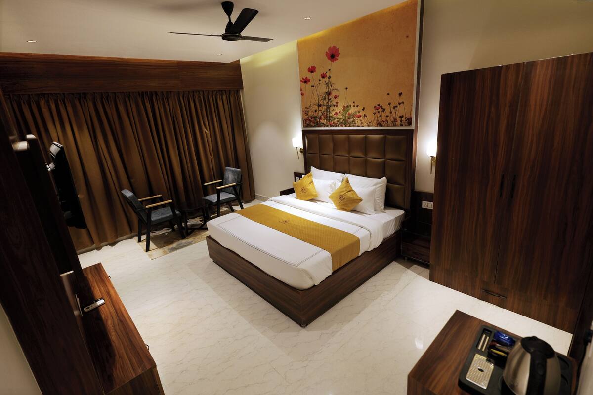 A hotel room with a bed, a desk, a chair, a wardrobe, and a ceiling fan.