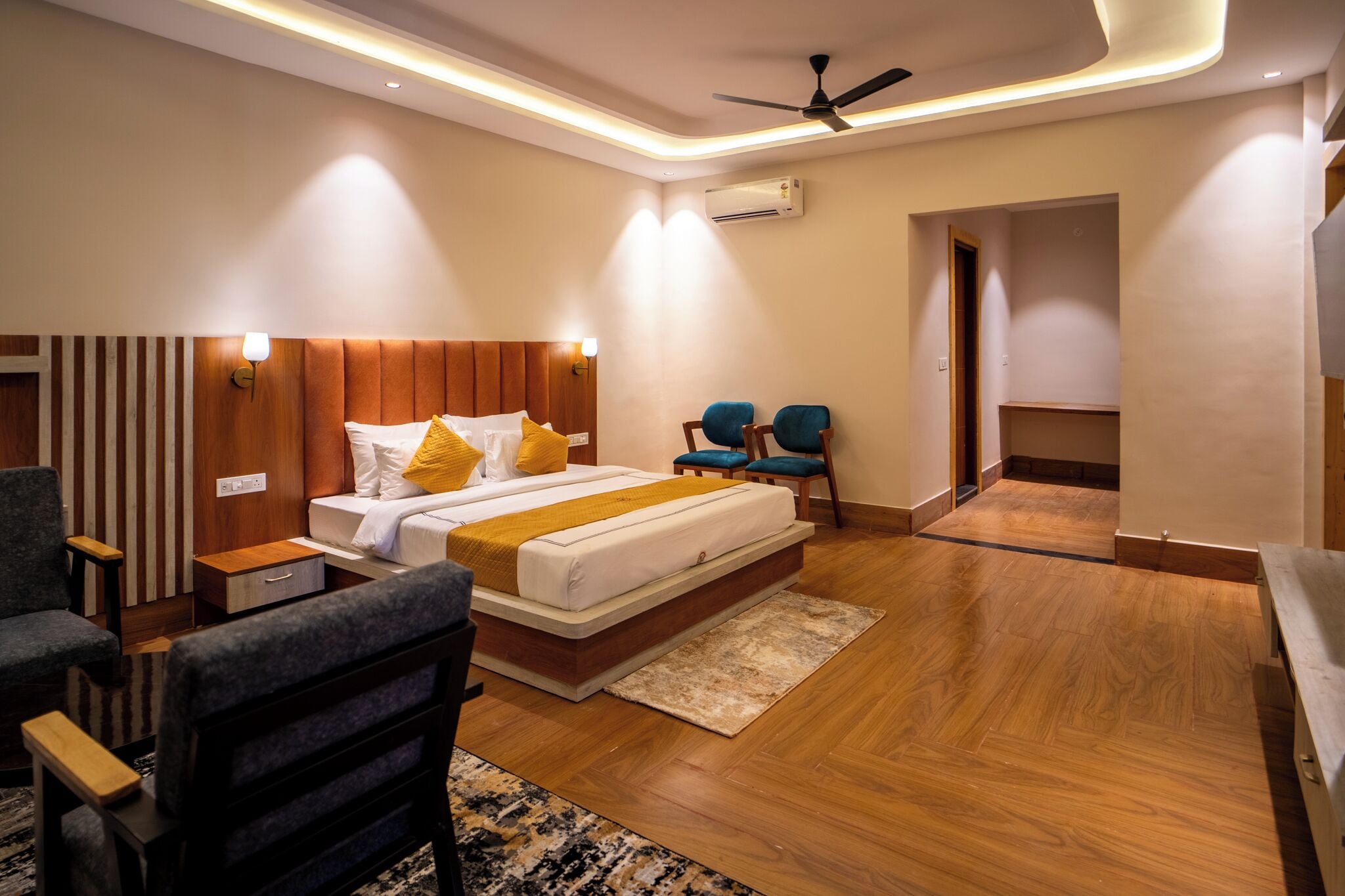 Una camera d'albergo moderna con un letto, due poltrone, una scrivania e una ventola a soffitto.
