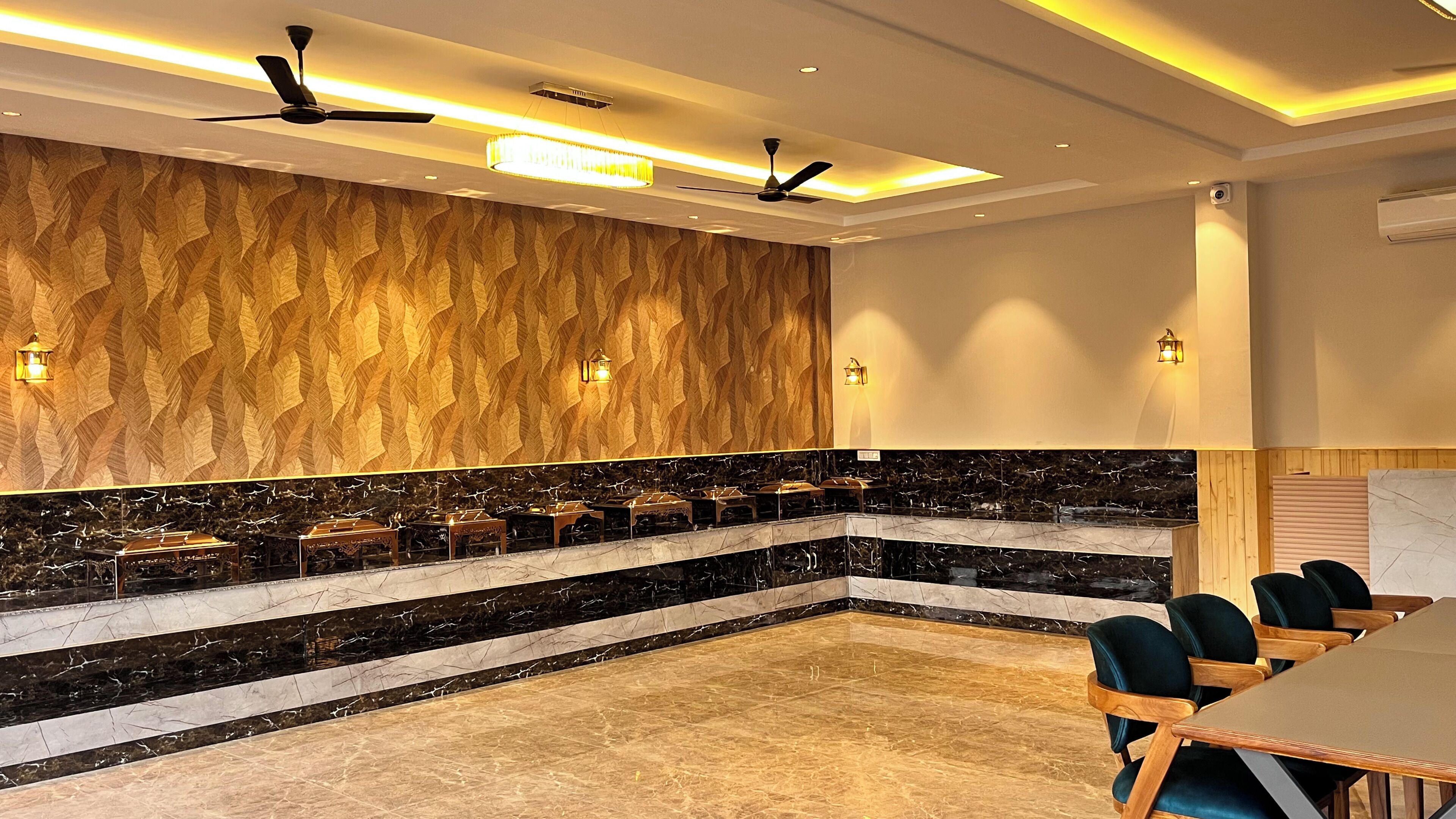 Un salón de conferencias con encimera de mármol, paneles de madera, ventiladores de techo y una mesa con sillas.