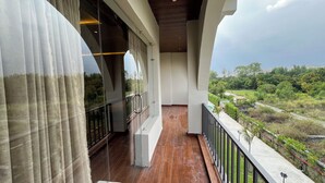 A balcony with a view of greenery and a clear sky.