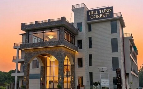 A multi-story hotel with a prominent entrance, a balcony, and a sign reading 'Hill Turn Corbett.'