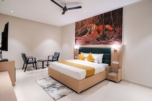 Un dormitorio con una cama, un escritorio, una silla, un televisor y un ventilador de techo.