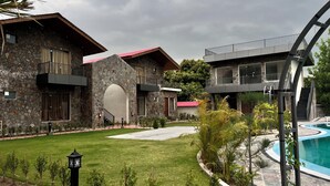 A stone building with balconies, a swimming pool, and a well-maintained lawn.