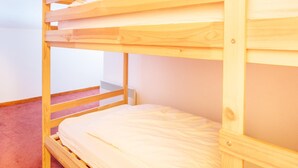 A bunk bed in a room with a plain wall and carpeted floor. - Cosy Apartment in Modane by Ski-lifts (Modane)