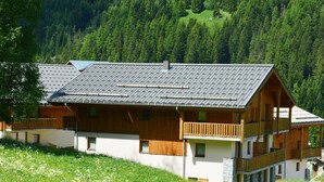 A two-story wooden chalet with a sloped roof, balconies, and a stone foundation. - Cosy Apartment in Modane by Ski-lifts (Modane)