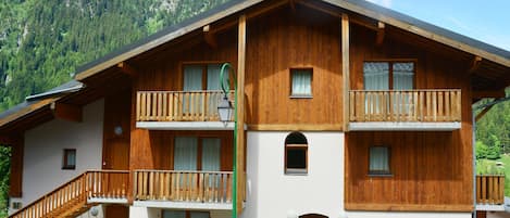Un edificio de estilo chalé con balcones de madera, una escalera y un cartel que indica que es un chalé.