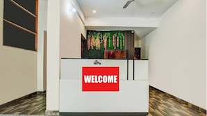 Una recepción con un cartel que dice 'WELCOME', una pared verde con plantas colgantes y un suelo estampado.