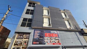 Un hotel llamado Eden con un gran letrero que anuncia servicio 24 horas, un número de contacto y comodidades como respaldo de energía y seguridad.