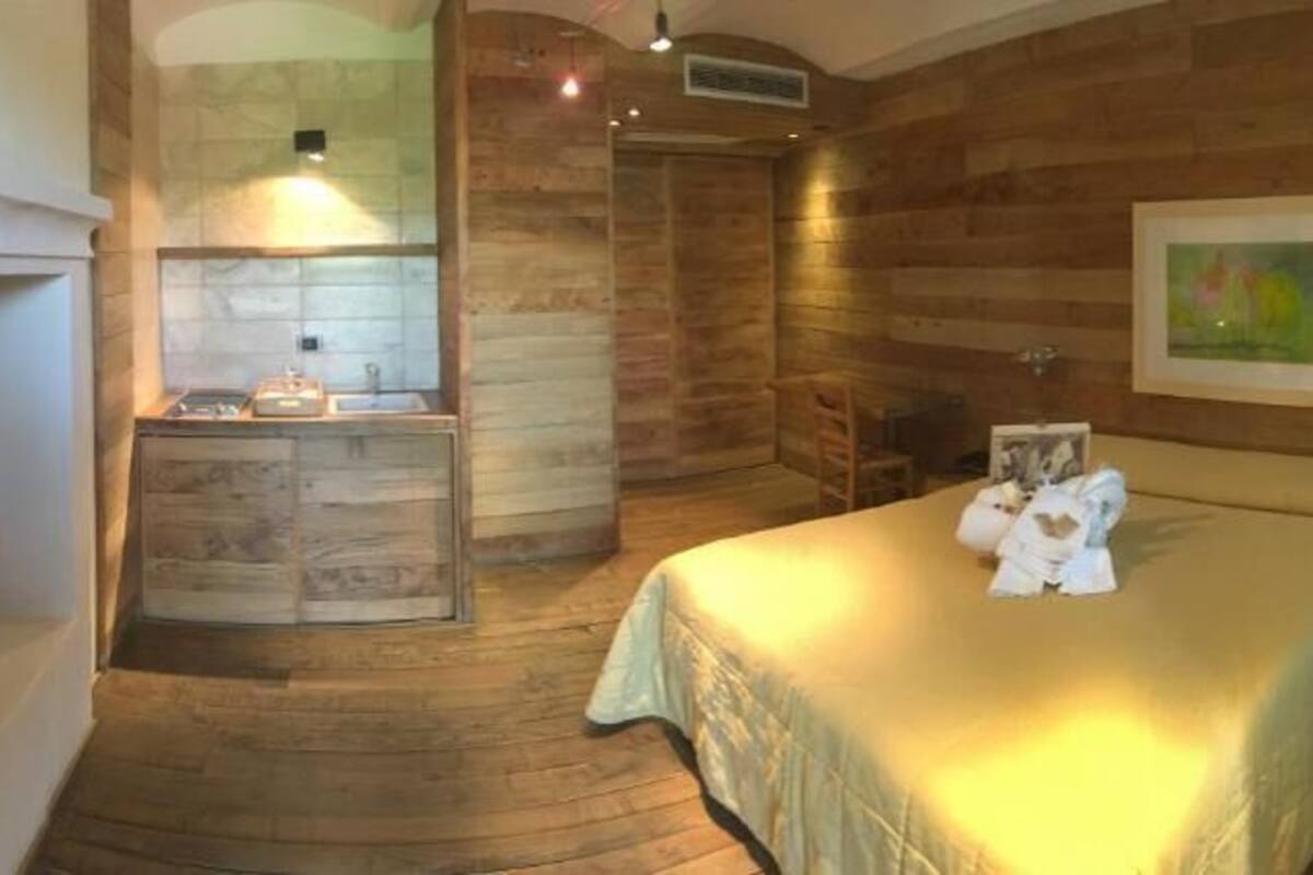 Ein Zimmer mit Holzboden, einem Bett, einem kleinen Tisch und einer Bank.