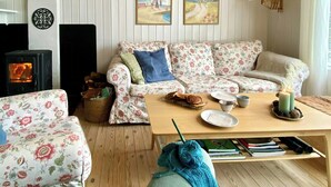A cozy living room with a sofa, a coffee table, and a fireplace. - Summer house by Tranum plantation and beach (Brovst)