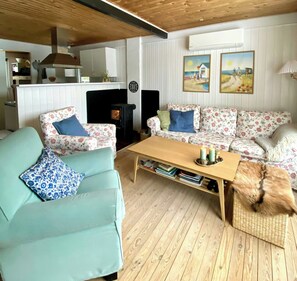 Una sala de estar con sofás de estampado floral, una mesa de centro de madera, una chimenea y un perro.