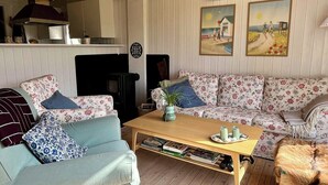 A cozy living room with a sofa, a coffee table, and a fireplace. - Summer house by Tranum plantation and beach (Brovst)