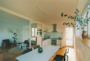 Moderni keittiö, jossa on ruokailutila, ruukussa oleva kasvi ja ikkunasta avautuva näkymä.