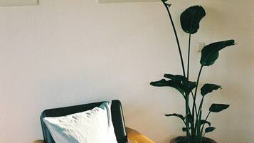 Ein Sessel mit Kissen, ein Blumentopf und architektonische Zeichnungen an der Wand.