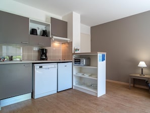 A compact kitchen with a dishwasher, microwave, and coffee maker. - Decent Stay in Art Village With Terrace (Pont-Aven)