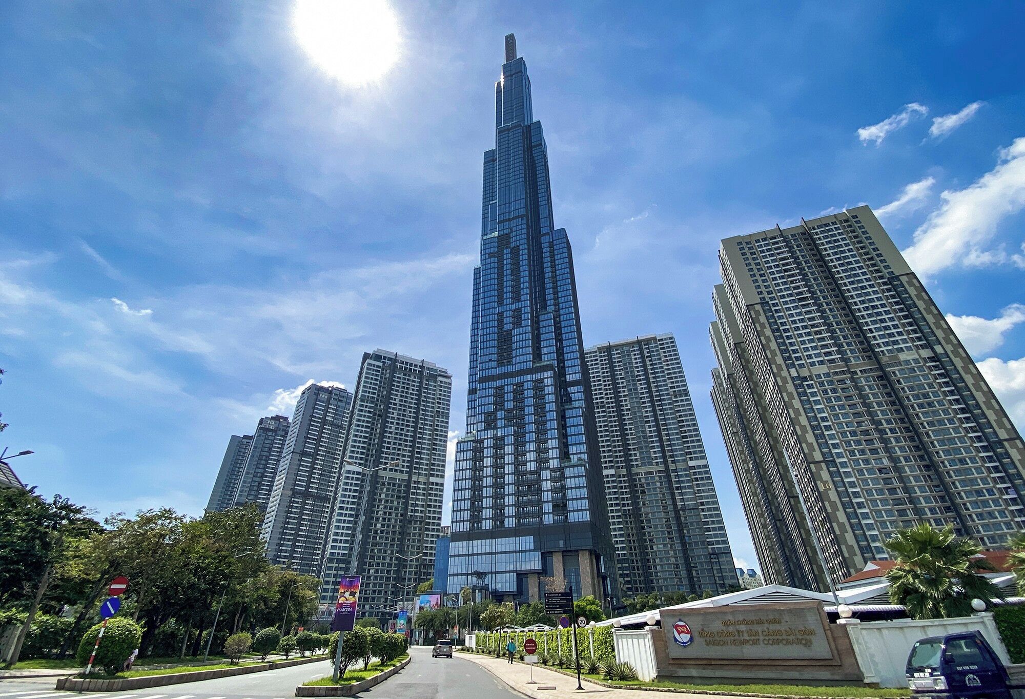 A tall skyscraper with a glass facade, surrounded by other high-rise buildings, under a clear sky.