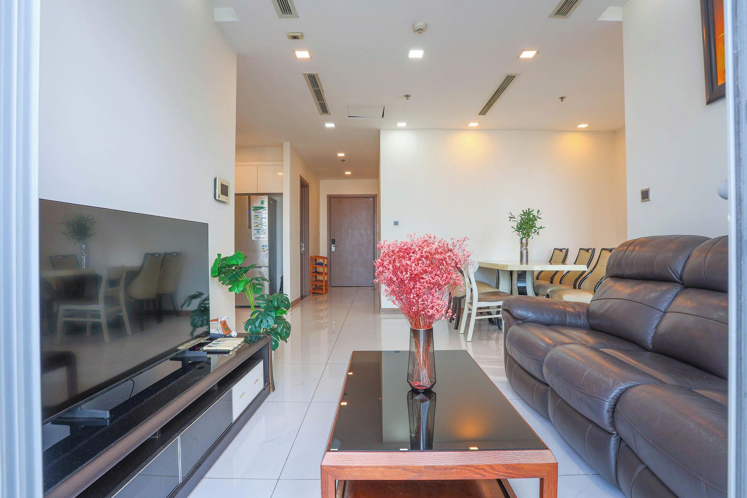 Een moderne woonkamer met een flatscreen-televisie, een bank, een salontafel en een vaas met bloemen.