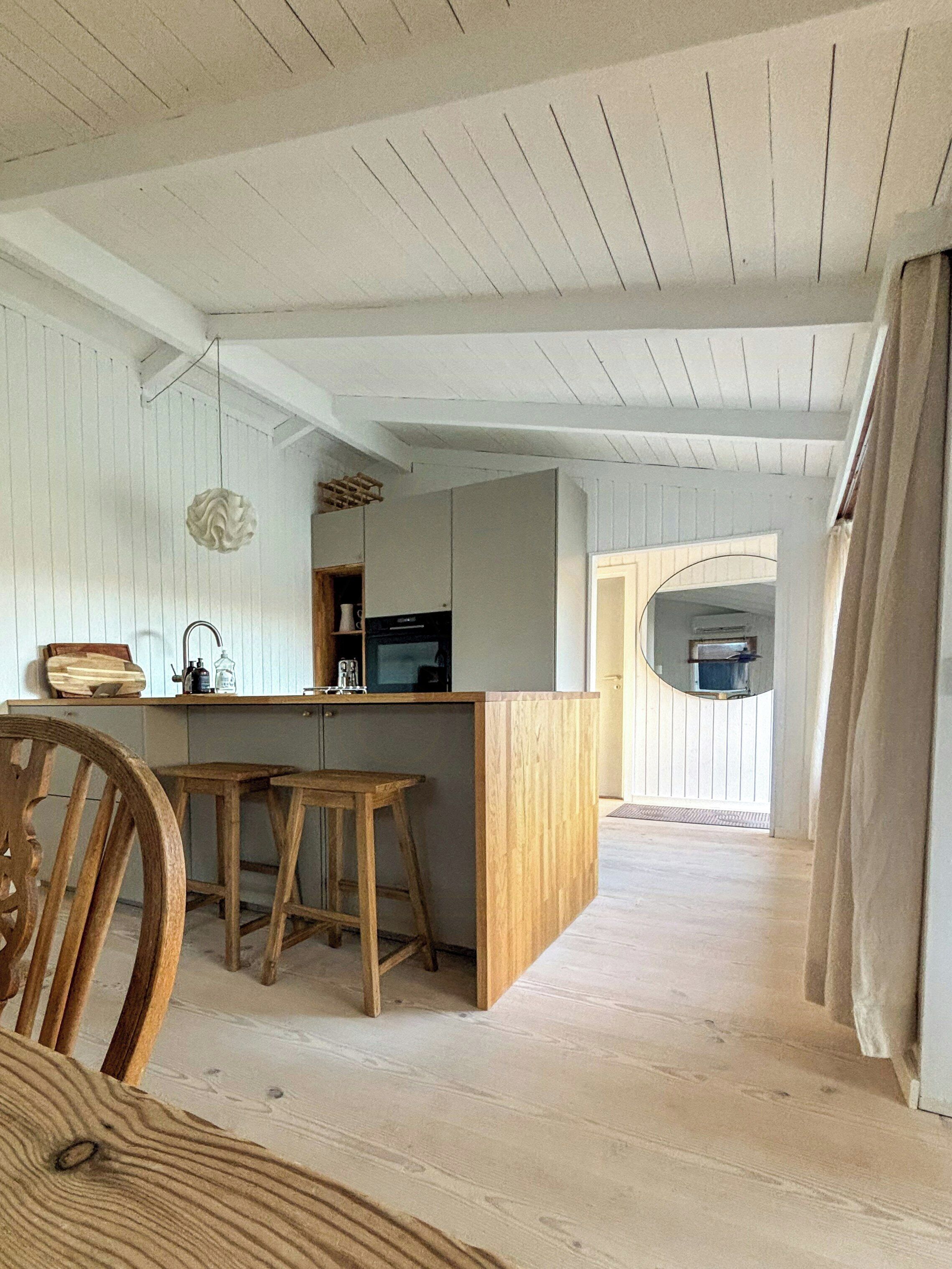 A kitchen with wooden stools, a bar counter, and a hanging light fixture.