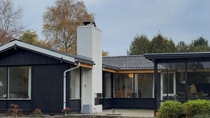 Ett modernt hus med en stor skorsten, ett garage och en välskött gräsmatta.