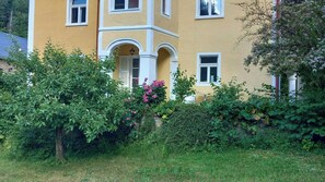Ein zweistöckiges Gebäude mit gelber Fassade, weißen Verzierungen und mehreren Fenstern.