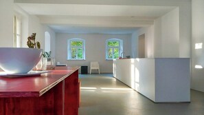 A modern kitchen with a wooden countertop, a white refrigerator, and two windows with green foliage. - Minimalist style apartment in Upper Palatinate (Neuenburg vorm Wald)