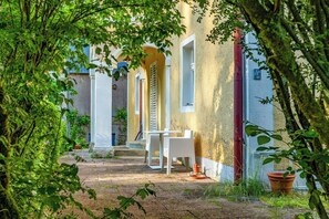 A courtyard with a white table and chairs, a staircase, and a building with a yellow facade. - Minimalist style apartment in Upper Palatinate (Neuenburg vorm Wald)